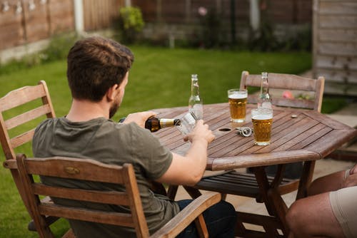 Em uma mesa de madeira redonda e um belo gramado ao redor, dois amigos tomam cerveja. O Cristão e a Bebida Alcoólica: O cristão pode tomar bebidas alcoólicas?