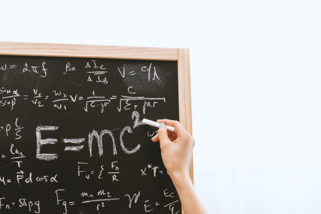 Uma pessoa escrevendo em um quadro negro a equação E=mc2. A importância da Relação “Tempo-espaço” na Relatividade de Einstein.