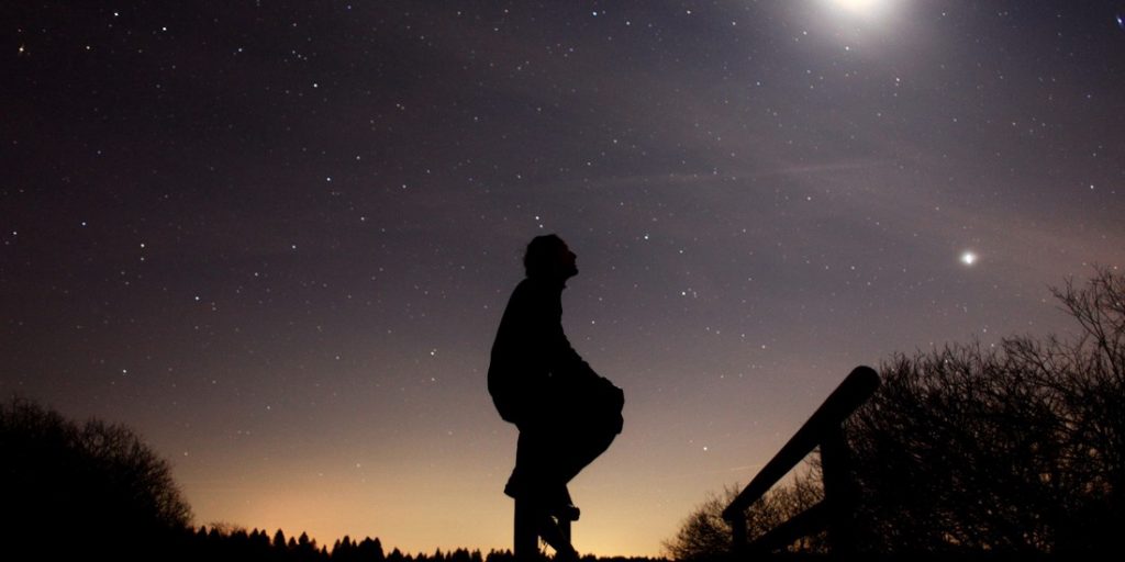 Uma pessoal em perfil no crepúsculo, observando as estrelas. O Sentido da Existência