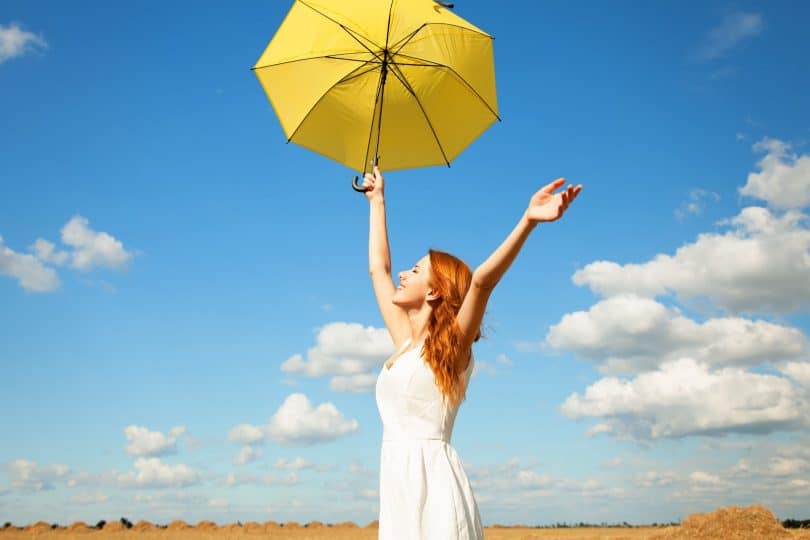 Uma Mulher com uma sombrinha amarela em um lindo céu azul. Viva o Agora. Agora!