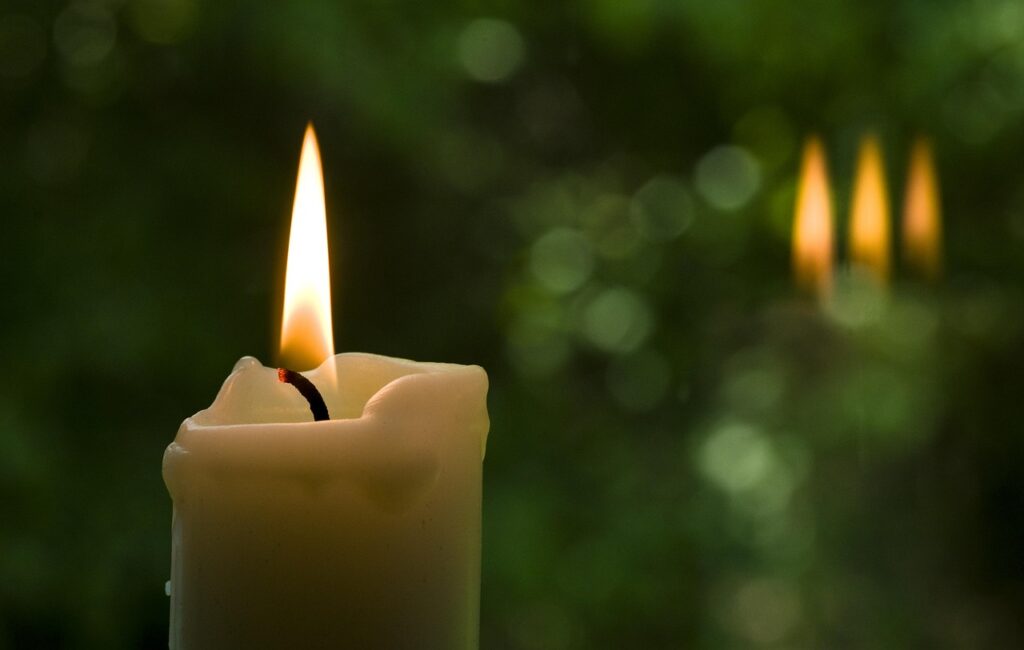 Uma Vela acesa com três sombras luminosas nos lembram a trindade